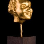 FAUN – fine gold 999, 120g, from series of grotesque heads 3.4 cm x 2.4 cm x 3.1 cm, height with plinth (ebony) 11.2 cm